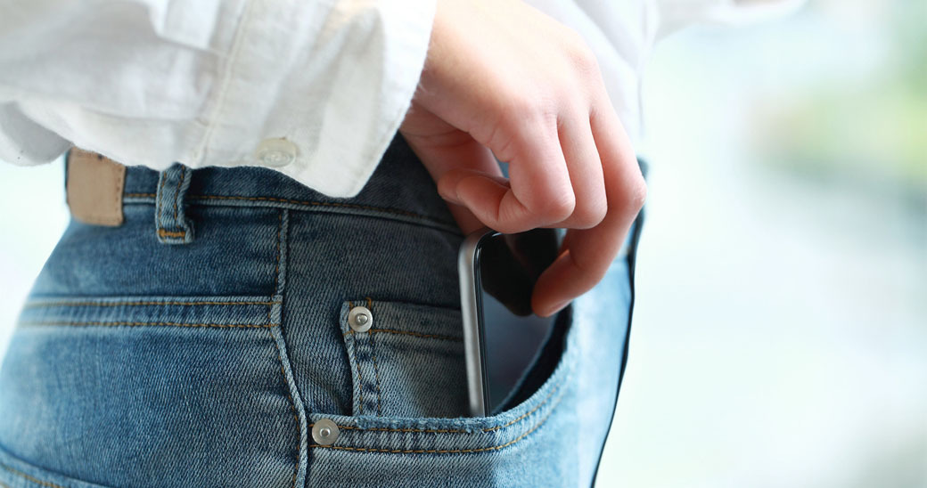 Hand reaching for mobile phone in pocket