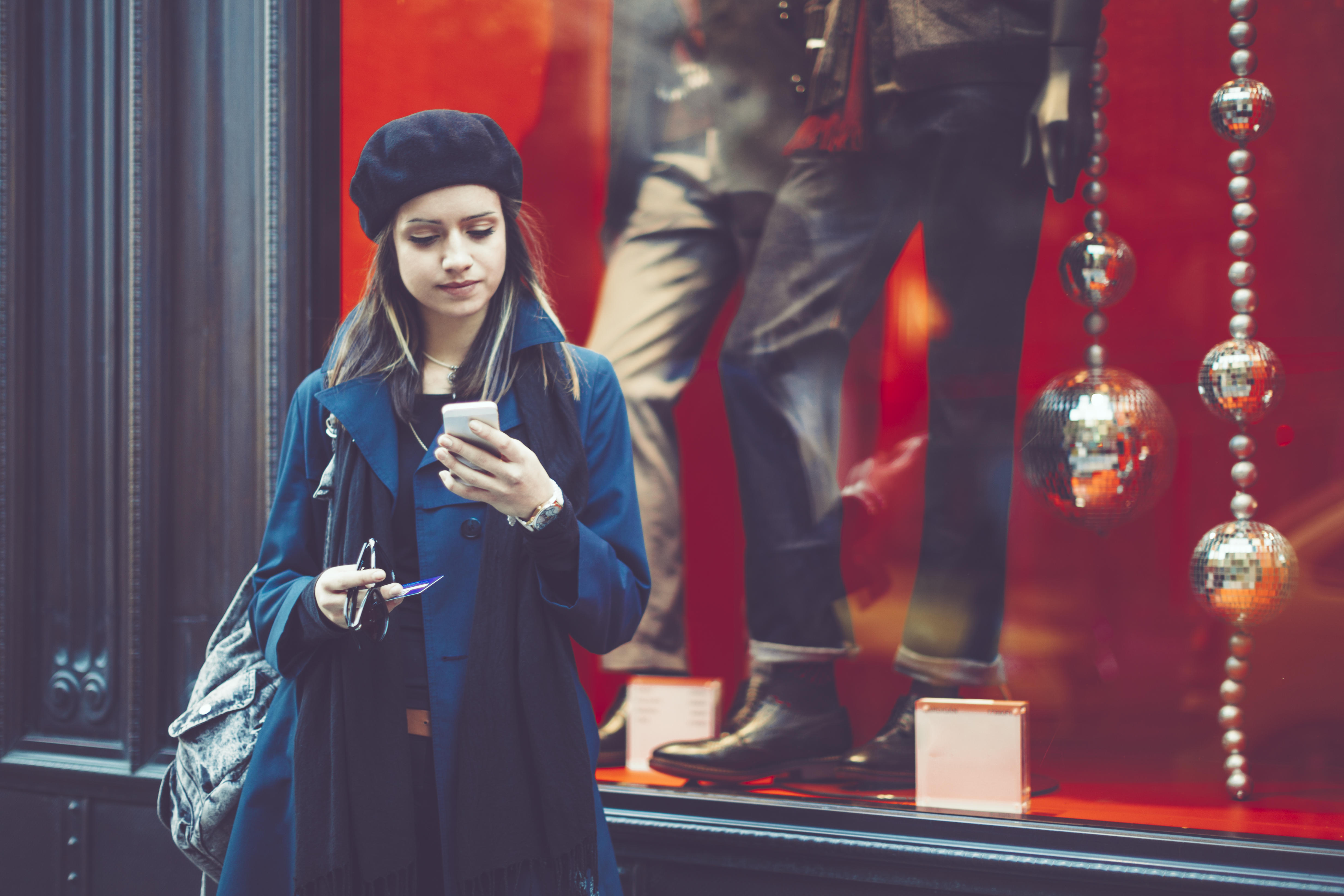 Woman-with-mobile-phone-in-front-of-shop-window